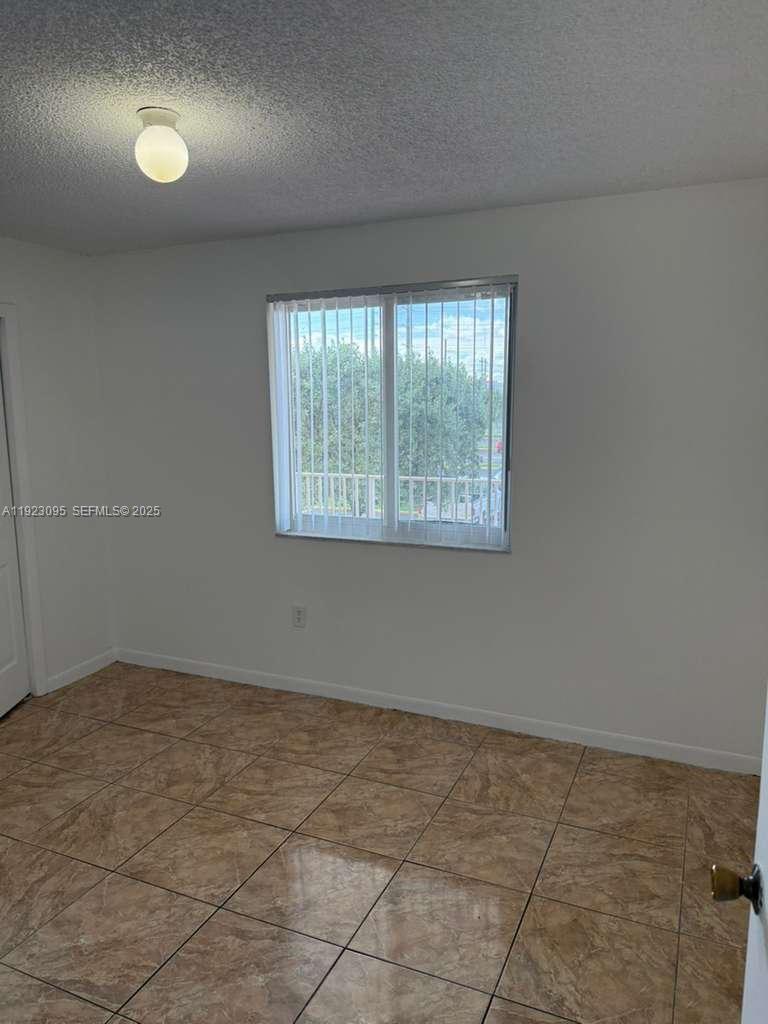 A room with white walls, a single window with vertical blinds, and tiled flooring — 7000 NW 186th St # 226, Hialeah FL 33015, HIALEAH, FL