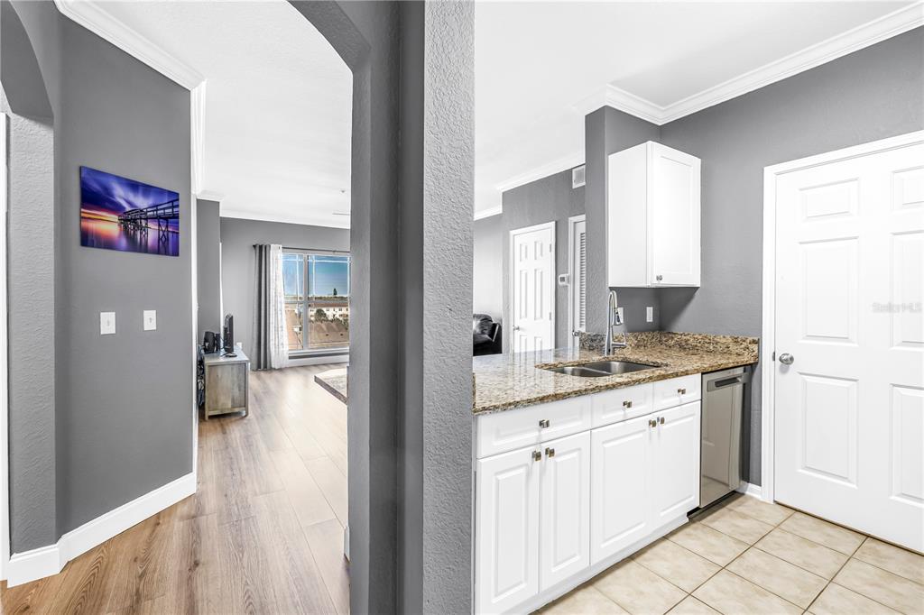 A kitchen with white cabinets and granite countertops overlooks a living area with wood flooring — 1216 S MISSOURI AVENUE UNIT 415, CLEARWATER, FL