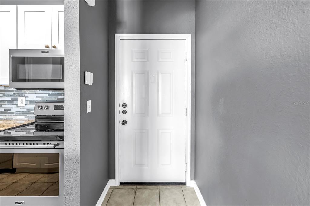 A white door stands in a kitchen area with gray walls and stainless steel appliances — 1216 S MISSOURI AVENUE UNIT 415, CLEARWATER, FL