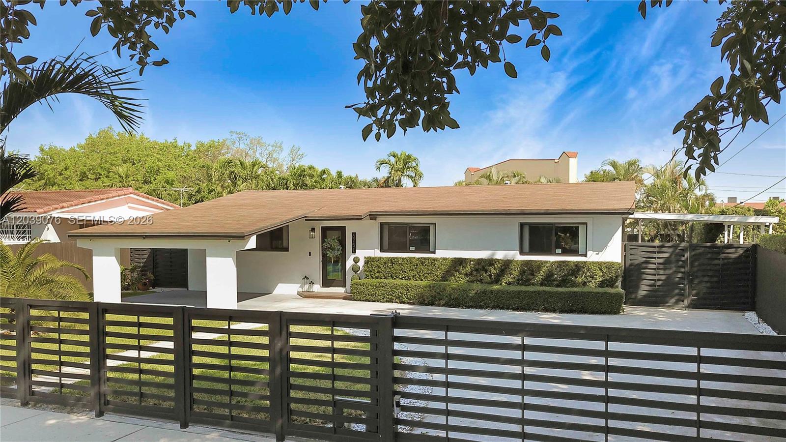 A single-story white house with a brown roof sits behind a modern black horizontal fence — 6751 SW 13th St, Miami FL 33144, MIAMI, FL