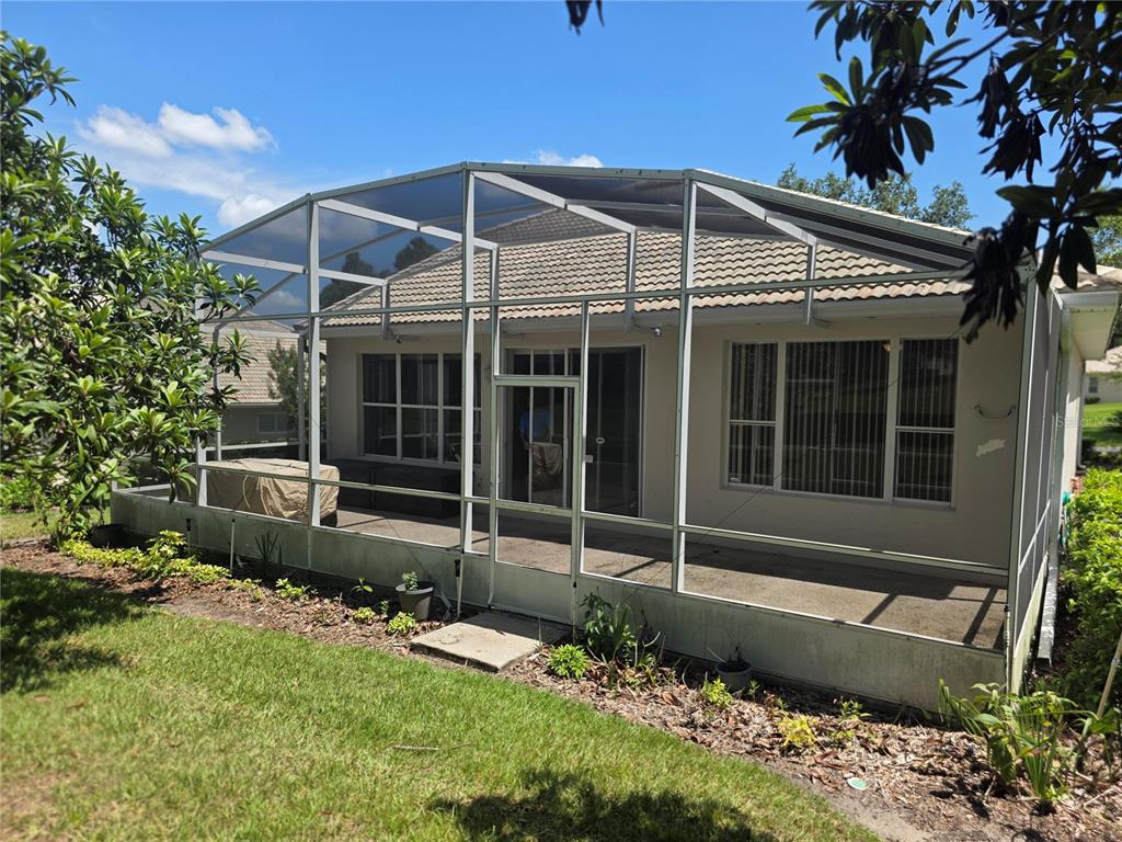 A screened-in patio with a concrete floor sits behind a house with a tiled roof — 2131 SAINT IVES COURT, CLERMONT, FL