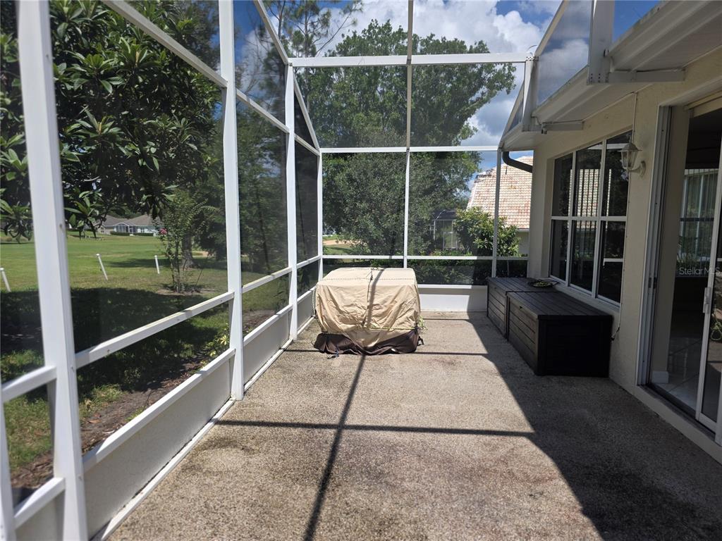 A screened-in patio with a concrete floor overlooks a grassy golf course area — 2131 SAINT IVES COURT, CLERMONT, FL