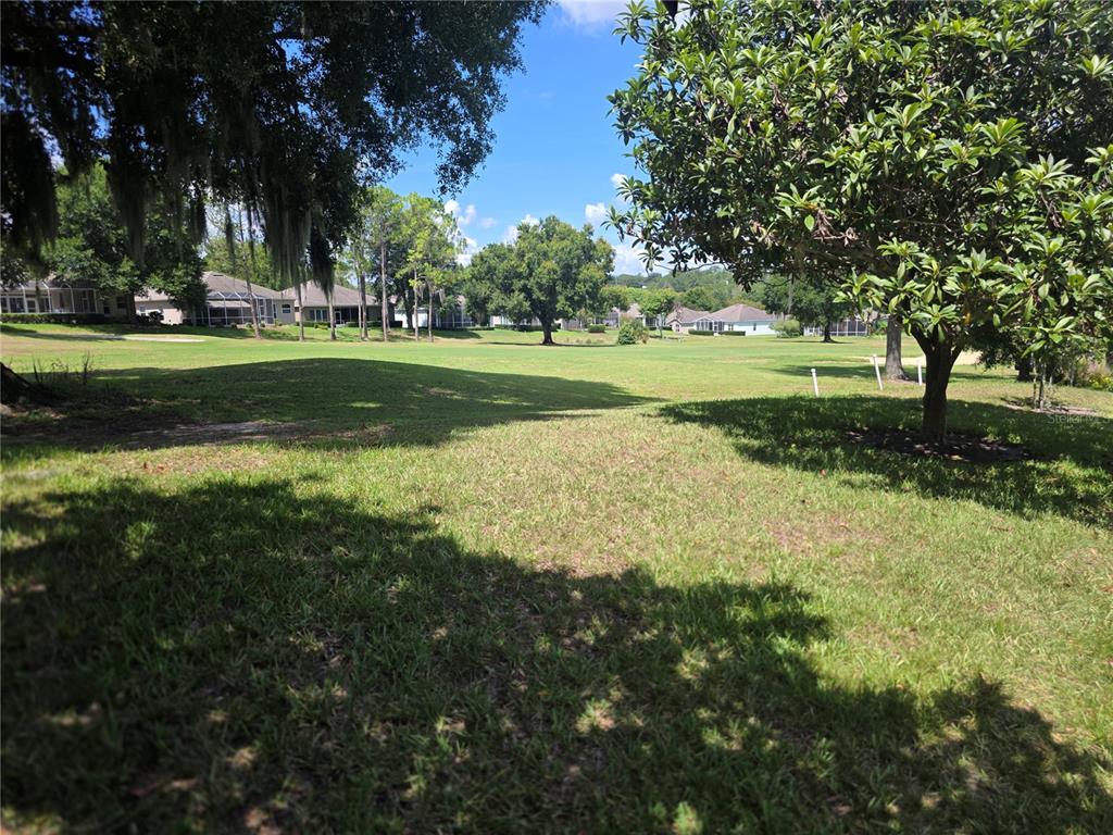 A view of a grassy golf course fairway framed by trees and residential homes — 2131 SAINT IVES COURT, CLERMONT, FL