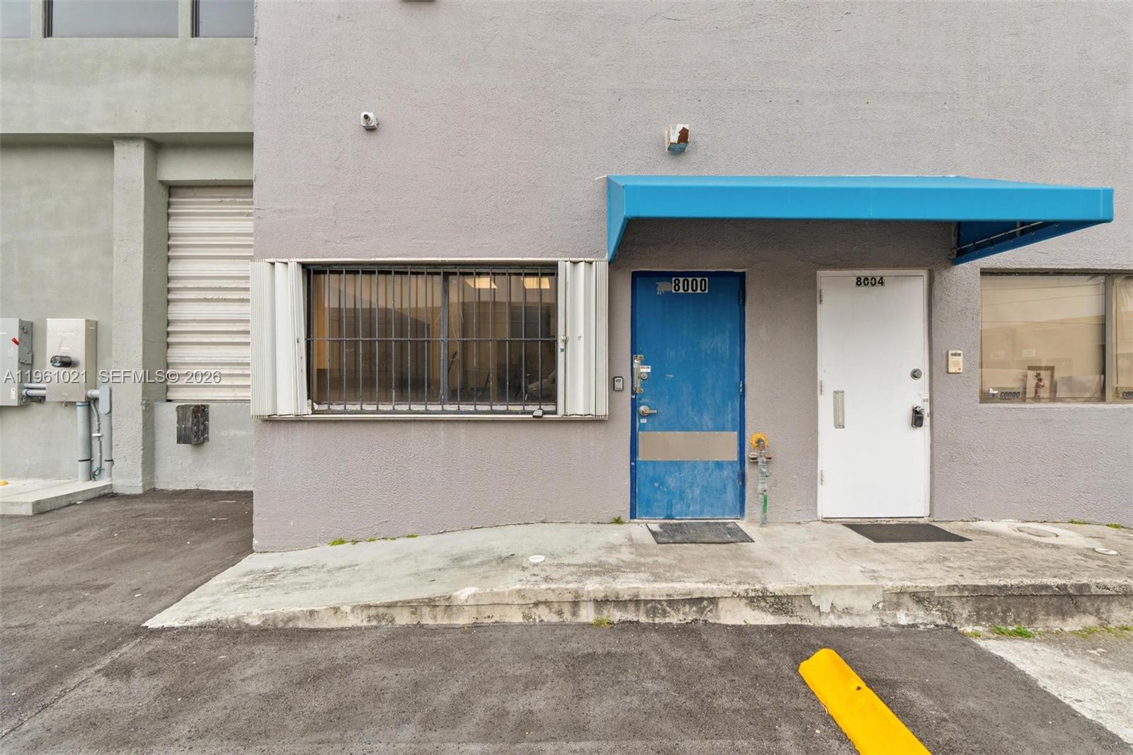 The exterior of a commercial building features a blue door, a white door, and a window — 8000 NW 68th St, Medley FL 33166, MEDLEY, FL
