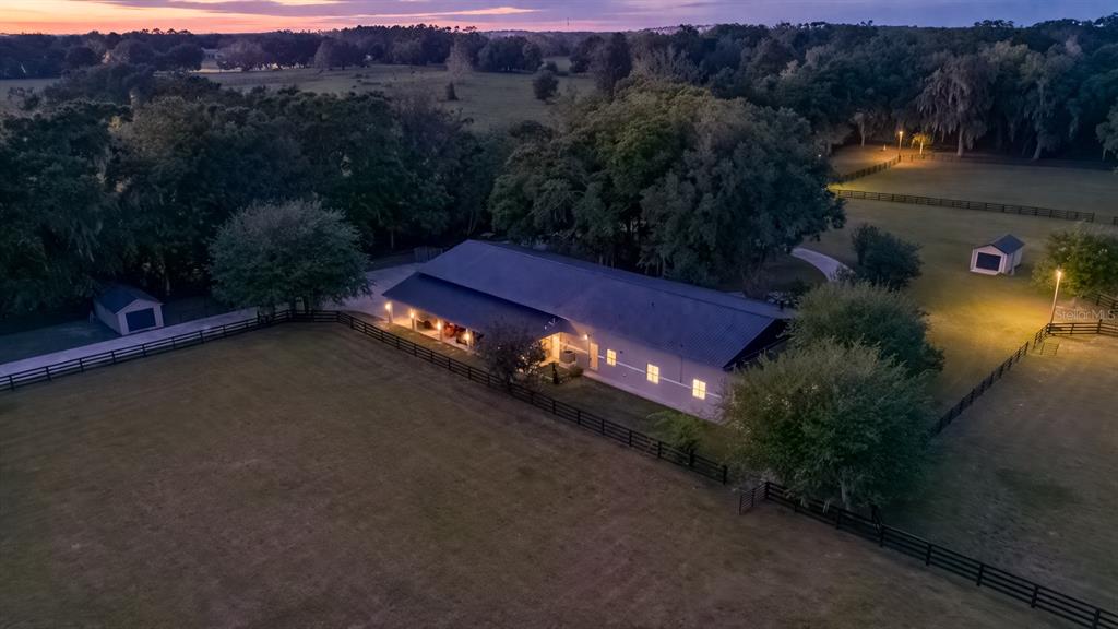 An aerial view shows a long, single-story building with a metal roof at dusk — 14650 NW 160TH AVENUE, WILLISTON, FL