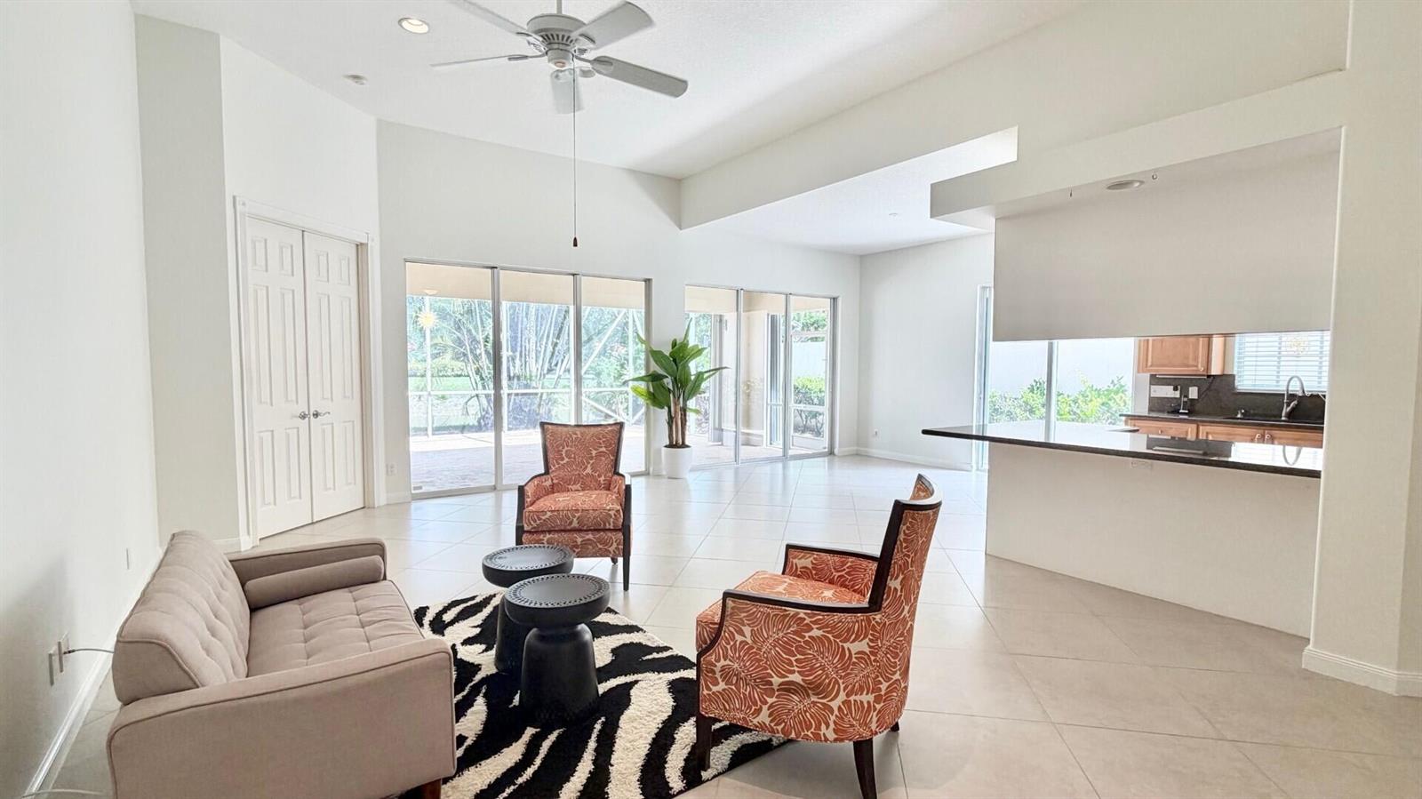 A living room with tile floors, a ceiling fan, and sliding glass doors to a patio — 2704 Irma Lake Drive, West Palm Beach FL 33411, WEST PALM BEACH, FL