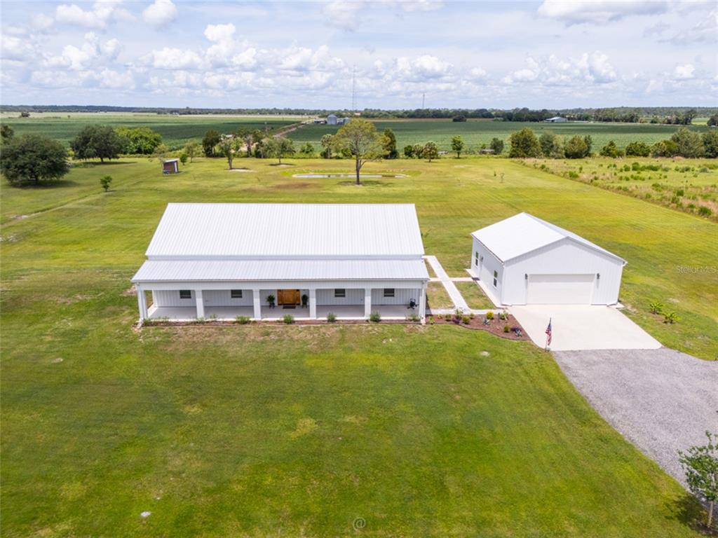 An aerial view shows a white metal-roofed house and detached garage on a grassy lot — 222 COUNTY ROAD 15, BUNNELL, FL