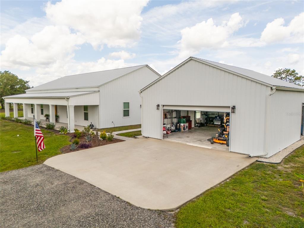 A white metal-sided house and detached garage sit on a grassy lot with a driveway — 222 COUNTY ROAD 15, BUNNELL, FL