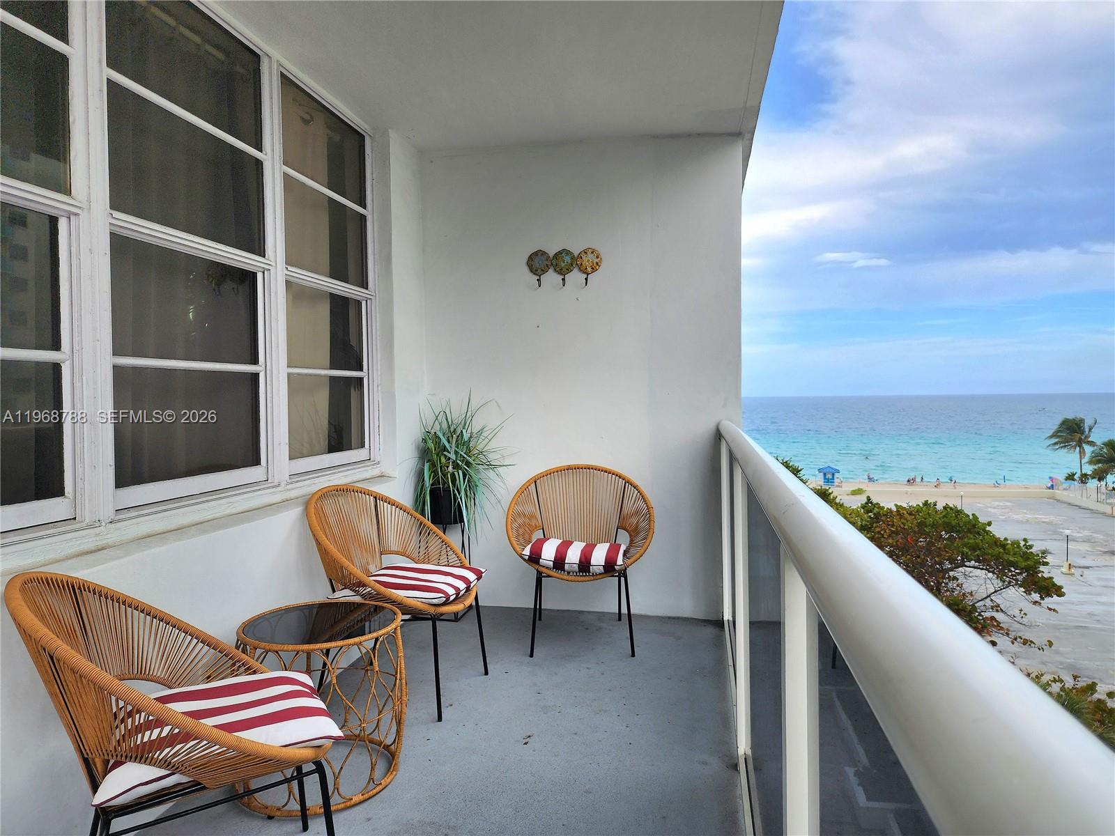 A balcony with three wicker chairs, a small table, and a view of the ocean — 3725 S Ocean Dr # 620, Hollywood FL 33019, HOLLYWOOD, FL