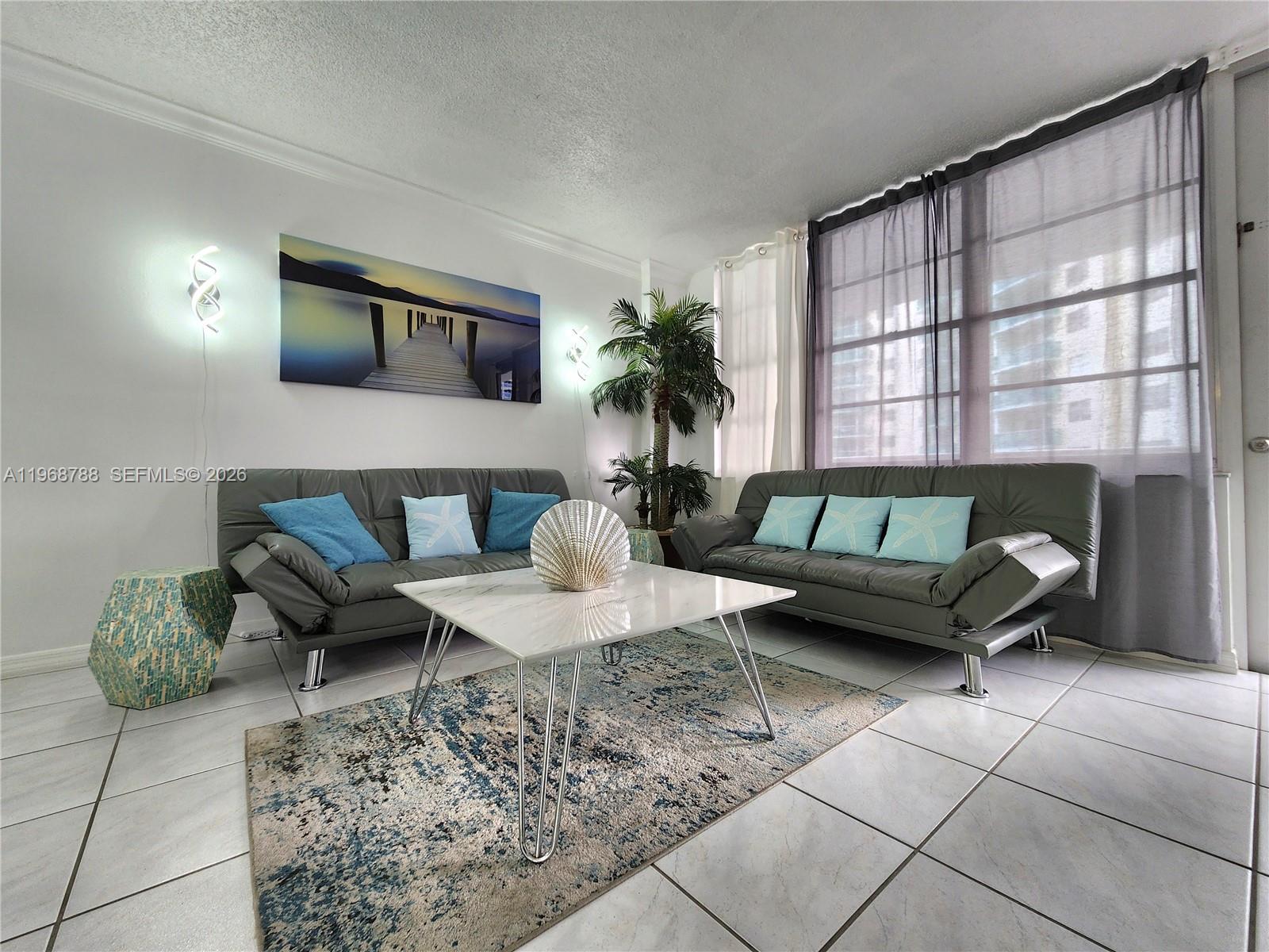 A living room features two gray sofas, a white coffee table, and a patterned rug — 3725 S Ocean Dr # 620, Hollywood FL 33019, HOLLYWOOD, FL