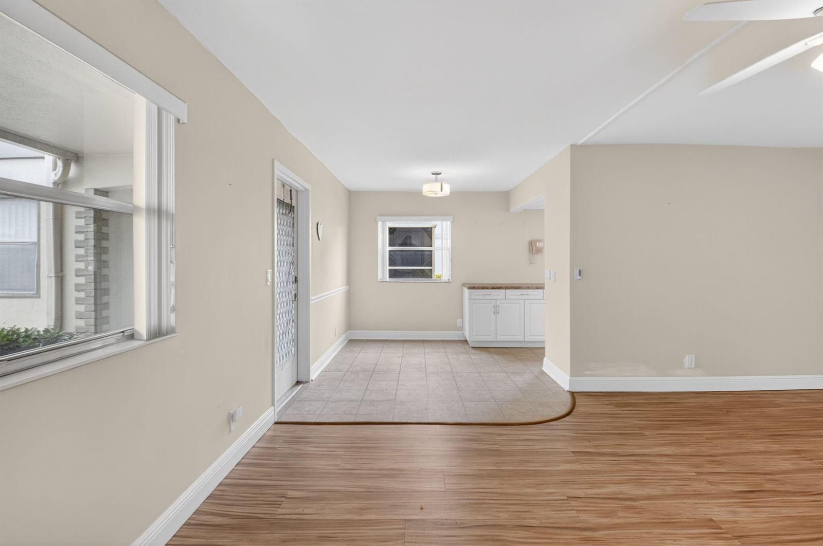 An interior view shows a dining area with tiled flooring transitioning to wood-look laminate flooring — 204 Flanders E, Delray Beach FL 33484, DELRAY BEACH, FL