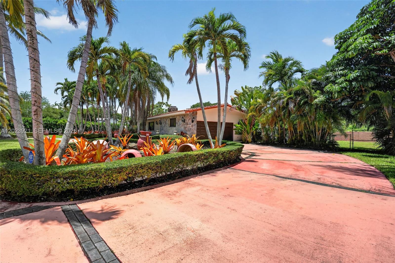 A paved driveway leads to a stone-faced house surrounded by palm trees and landscaping — 8461 SW 68th St Rd, Miami FL 33143, MIAMI, FL