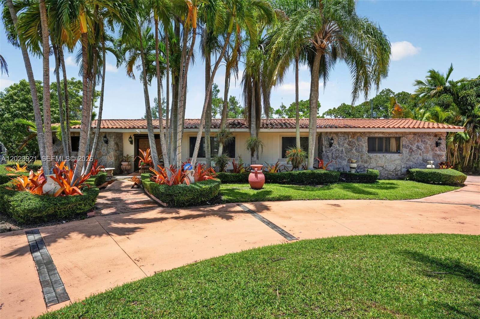 A single-story house features a stone facade, a tiled roof, and a palm-lined front yard — 8461 SW 68th St Rd, Miami FL 33143, MIAMI, FL