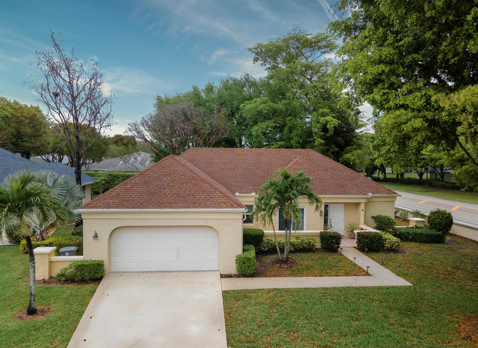 A single-story house with a tan stucco exterior, a brown shingled roof, and a garage — 10195 Greentrail Drive, Boynton Beach FL 33436, BOYNTON BEACH, FL