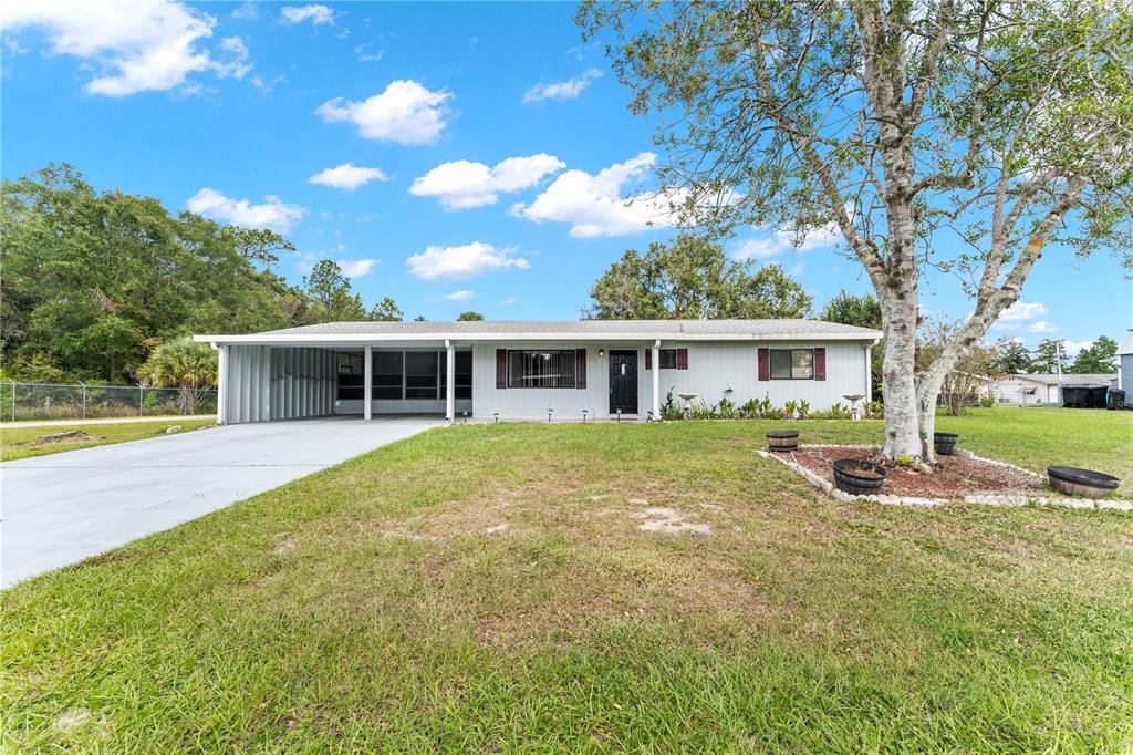 A single-story house with a carport, gray siding, and a large tree in the yard — 9981 SW 103RD PLACE, OCALA, FL