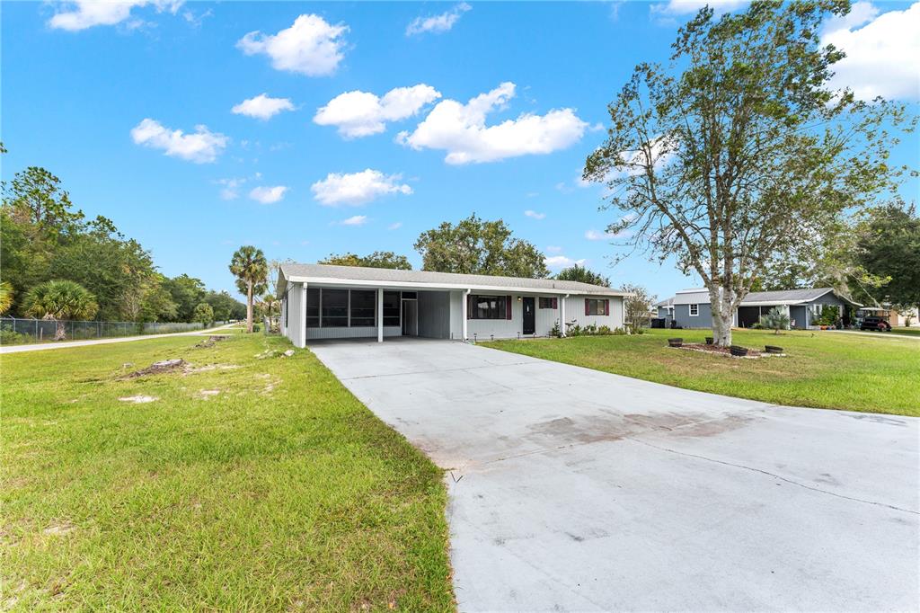 A single-story house with a concrete driveway, a carport, and a large front lawn — 9981 SW 103RD PLACE, OCALA, FL