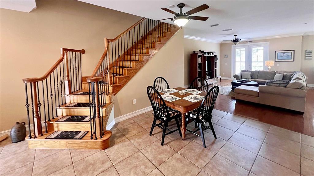 An open-concept interior features a wooden staircase, tile flooring, and a kitchen in the background — 1266 RIBOLLA DRIVE, PALM HARBOR, FL