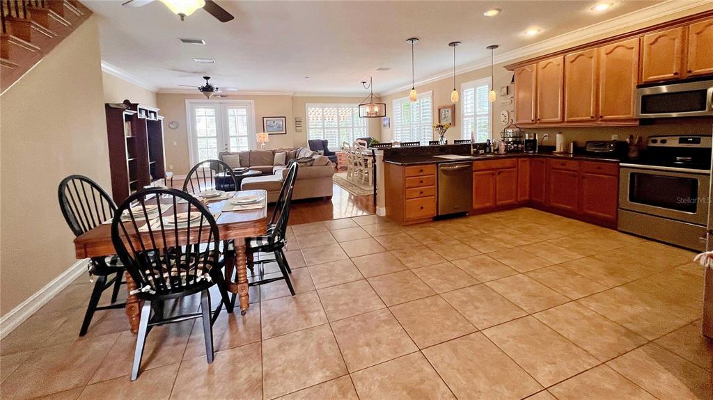 A dining area with a wooden staircase, tile flooring, and an adjacent living room — 1266 RIBOLLA DRIVE, PALM HARBOR, FL