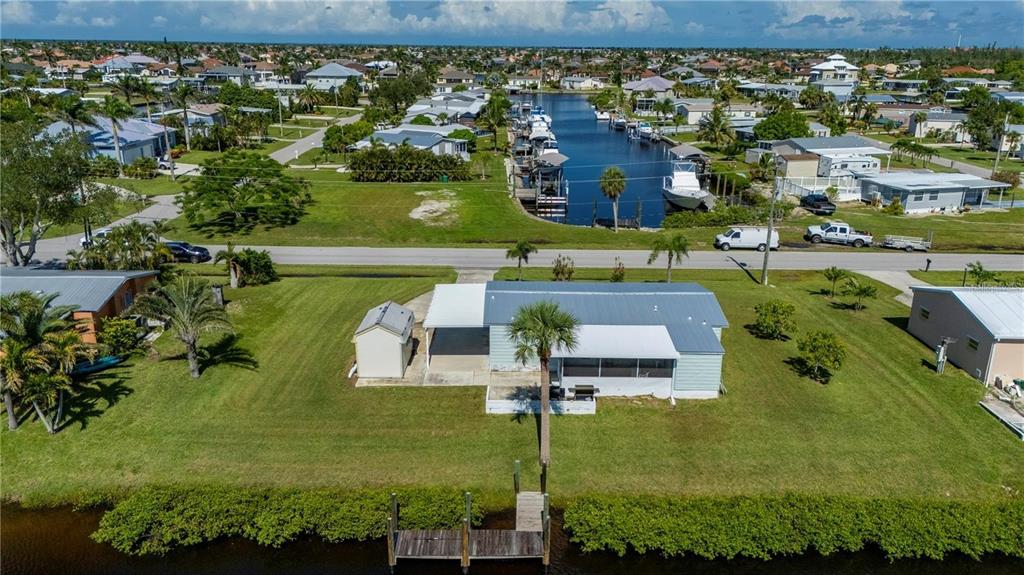An aerial view shows a single-story house with a dock on a canal — 4220 DELTONA DRIVE, PUNTA GORDA, FL