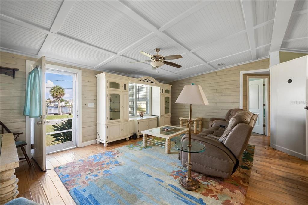 A living room features wood-paneled walls, a coffered ceiling, a ceiling fan, and a waterfront view — 4220 DELTONA DRIVE, PUNTA GORDA, FL