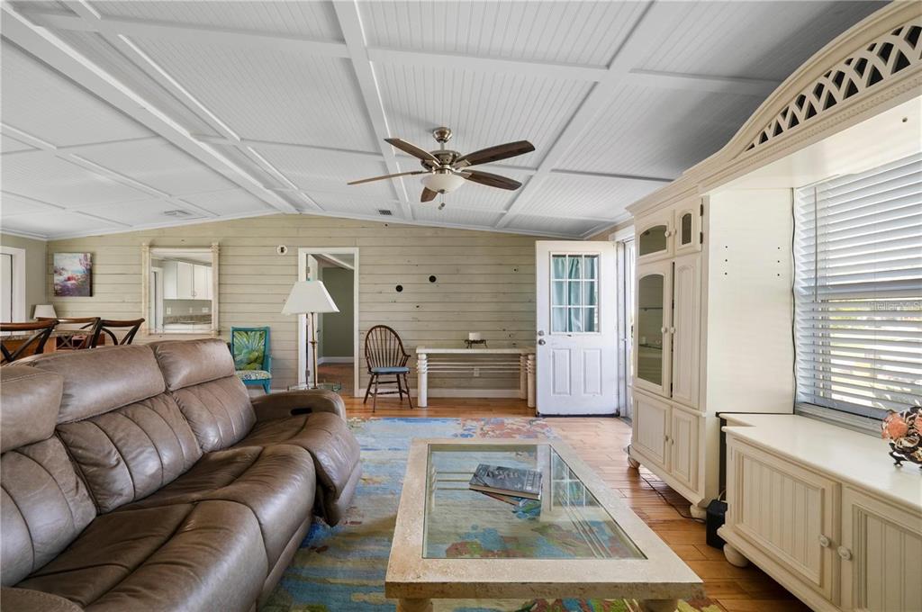 A living room features a coffered ceiling, wood-plank walls, a brown sofa, and a coffee table — 4220 DELTONA DRIVE, PUNTA GORDA, FL