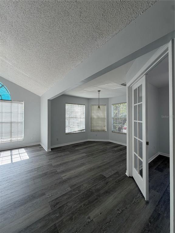 An interior view shows a room with gray wood-look flooring, vaulted ceilings, and French doors — 645 STAFFORD TERRACE UNIT 156, ALTAMONTE SPRINGS, FL