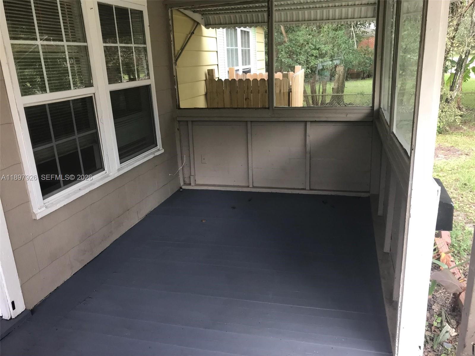 A covered porch features a painted dark gray floor, screen walls, and a windowed exterior wall — 2748 Broadway # 0, Jacksonville FL 32254, JACKSONVILLE, FL
