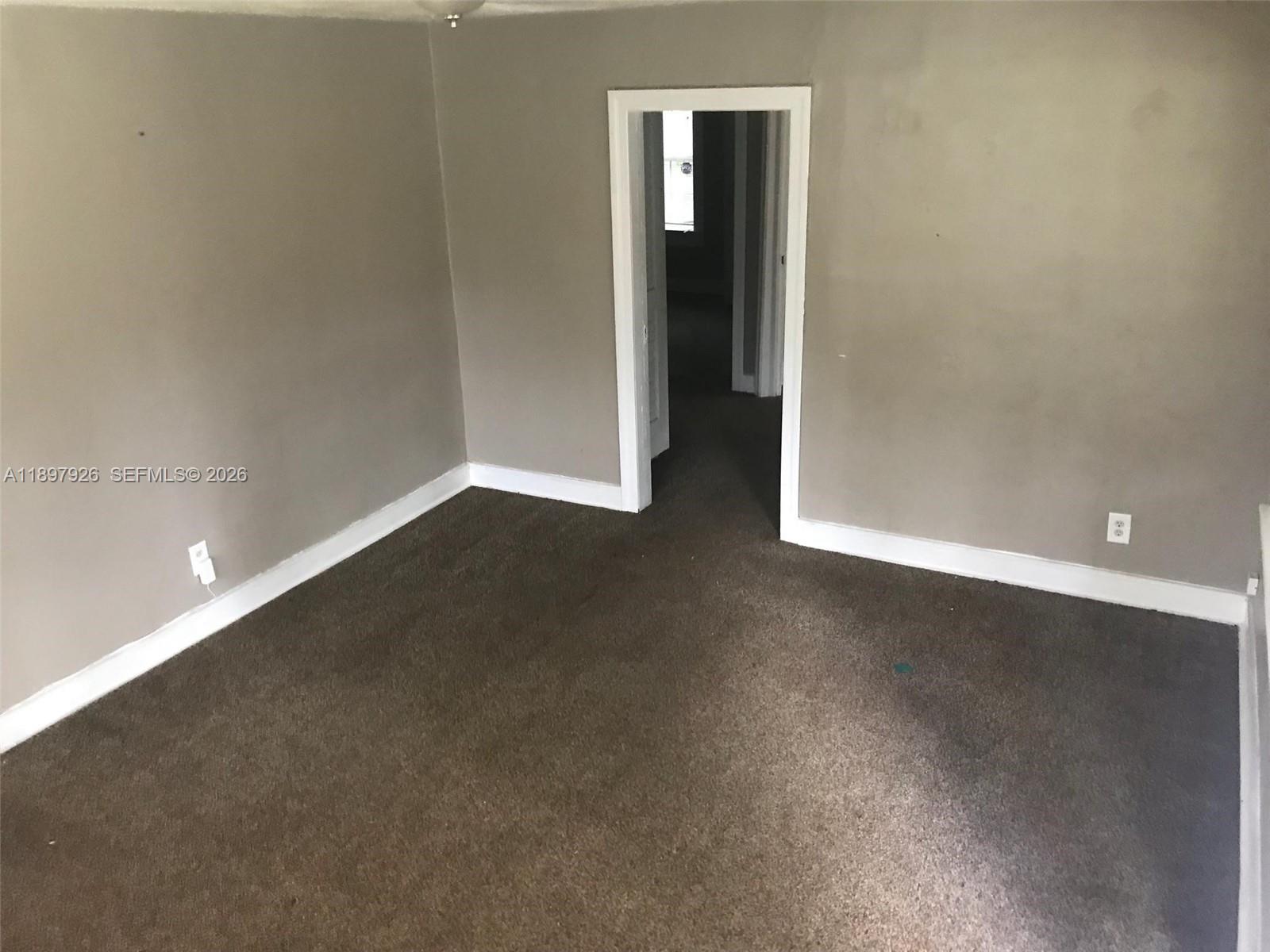 An empty room with gray walls, brown carpeting, and a doorway leading to another room — 2748 Broadway # 0, Jacksonville FL 32254, JACKSONVILLE, FL