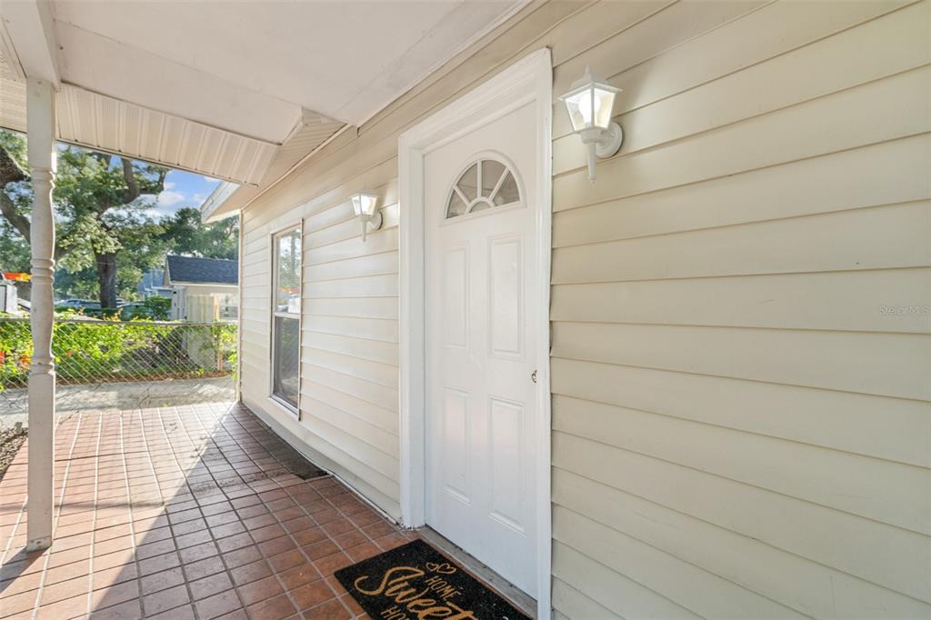 A white front door with a small arched window sits on a covered porch — 2116 E ELLICOTT STREET, TAMPA, FL
