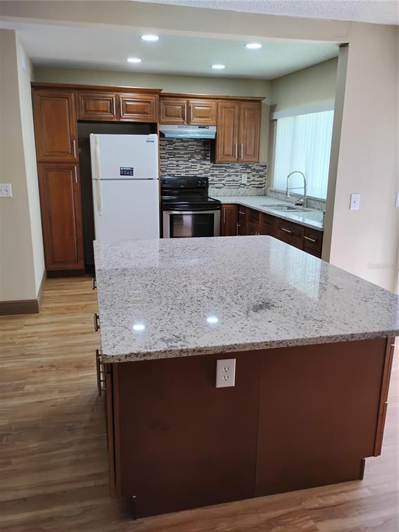 A kitchen features wood cabinets, granite countertops, a large island, and stainless steel appliances — 11721 RAINTREE DRIVE, TAMPA, FL