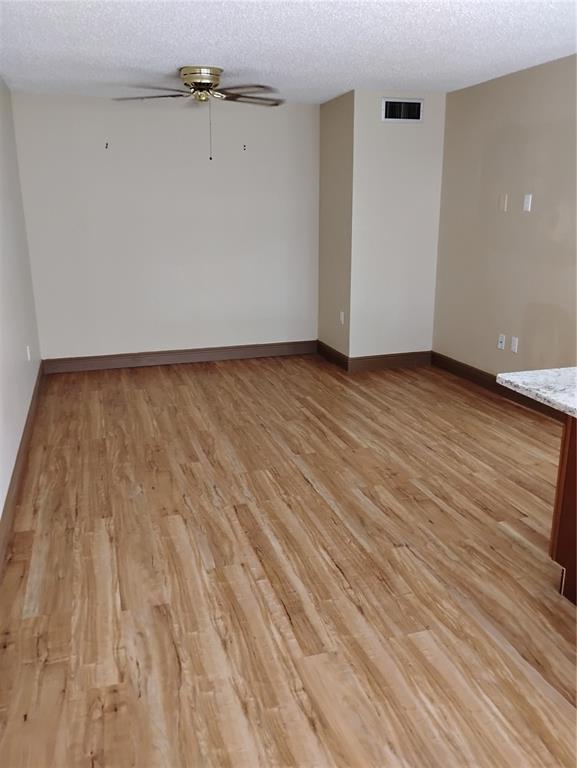 An empty room with light wood-look flooring, beige walls, and a ceiling fan — 11721 RAINTREE DRIVE, TAMPA, FL