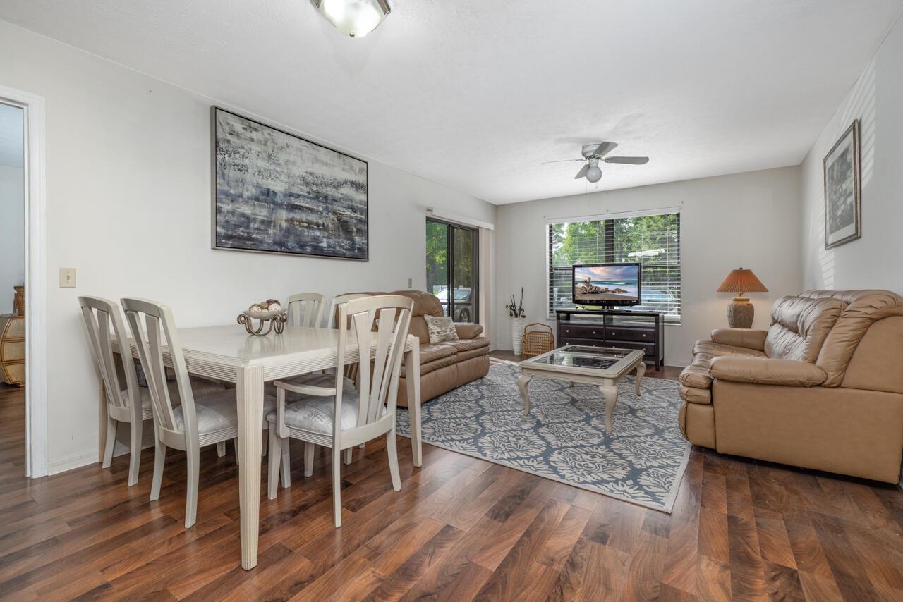 A living and dining room with wood-look flooring, beige leather sofas, and a patterned rug — 6537 SE Federal Highway # 101, Stuart FL 34997, STUART, FL