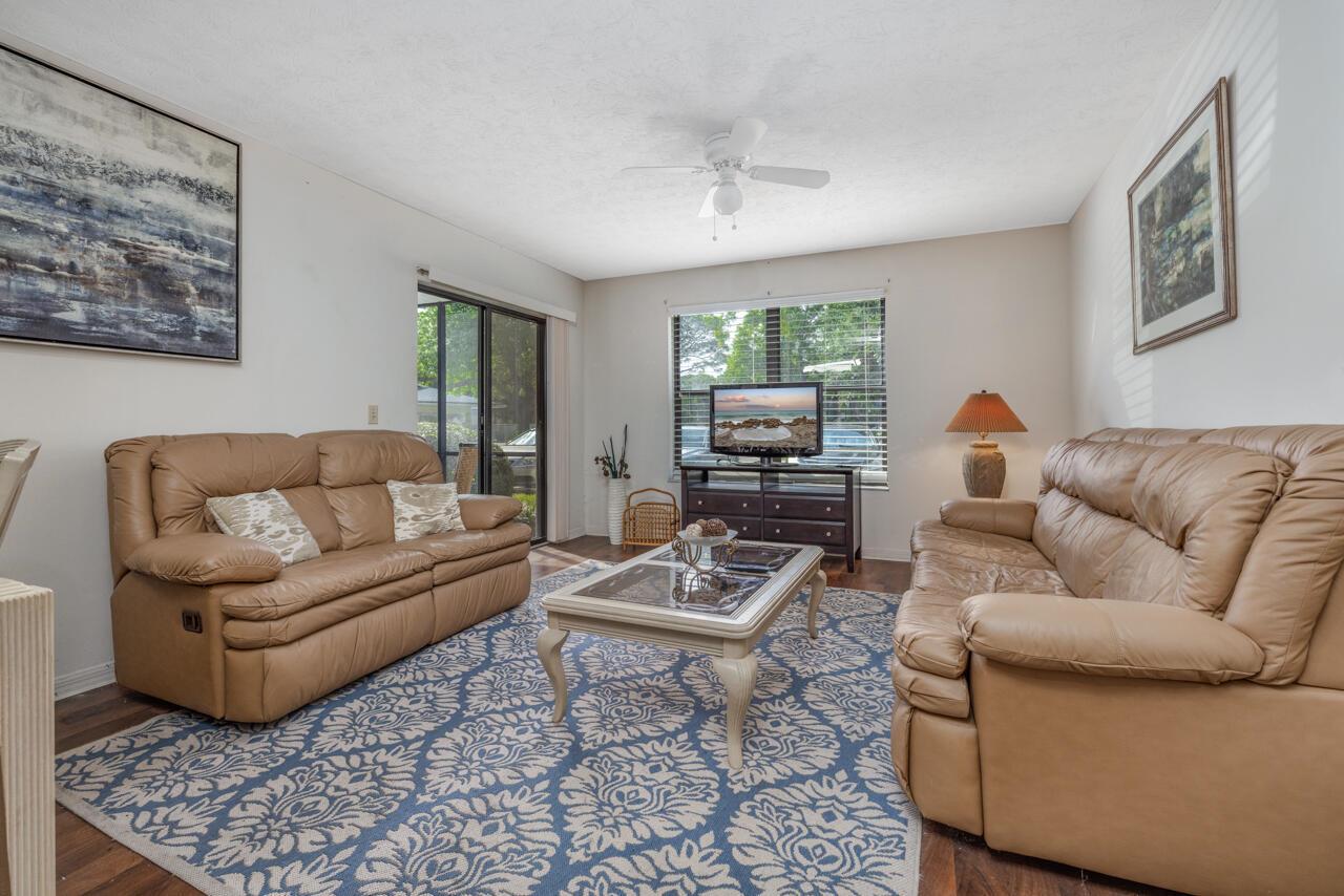 A living room features two tan leather sofas, a patterned blue rug, and a television — 6537 SE Federal Highway # 101, Stuart FL 34997, STUART, FL
