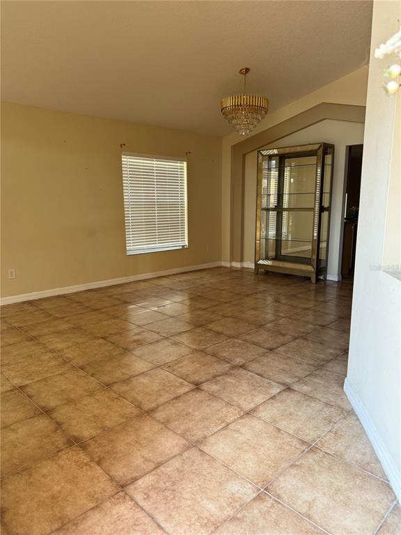 A dining room features tan tile flooring, a crystal chandelier, and a glass display cabinet — 5427 BRYCE CANYON DRIVE, KISSIMMEE, FL