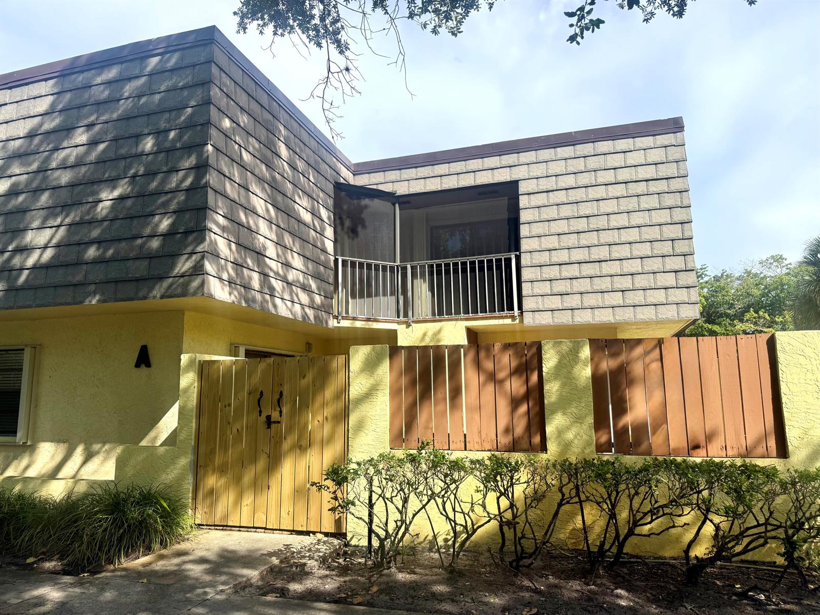A two-story building with yellow stucco walls, a wooden gate, and an upper-level balcony — 3100 SE Brook Street, Stuart FL 34997, STUART, FL