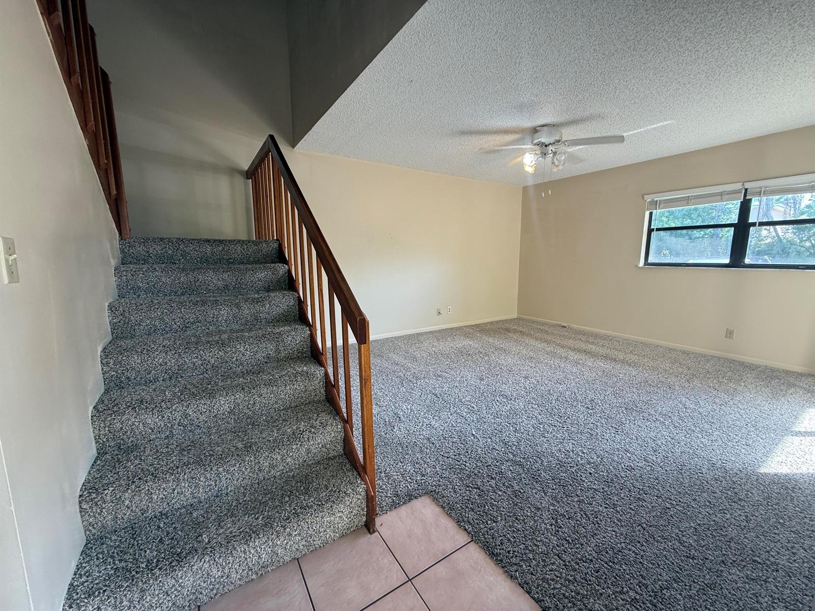 A carpeted living room features a staircase with a wooden railing and a ceiling fan — 3100 SE Brook Street, Stuart FL 34997, STUART, FL