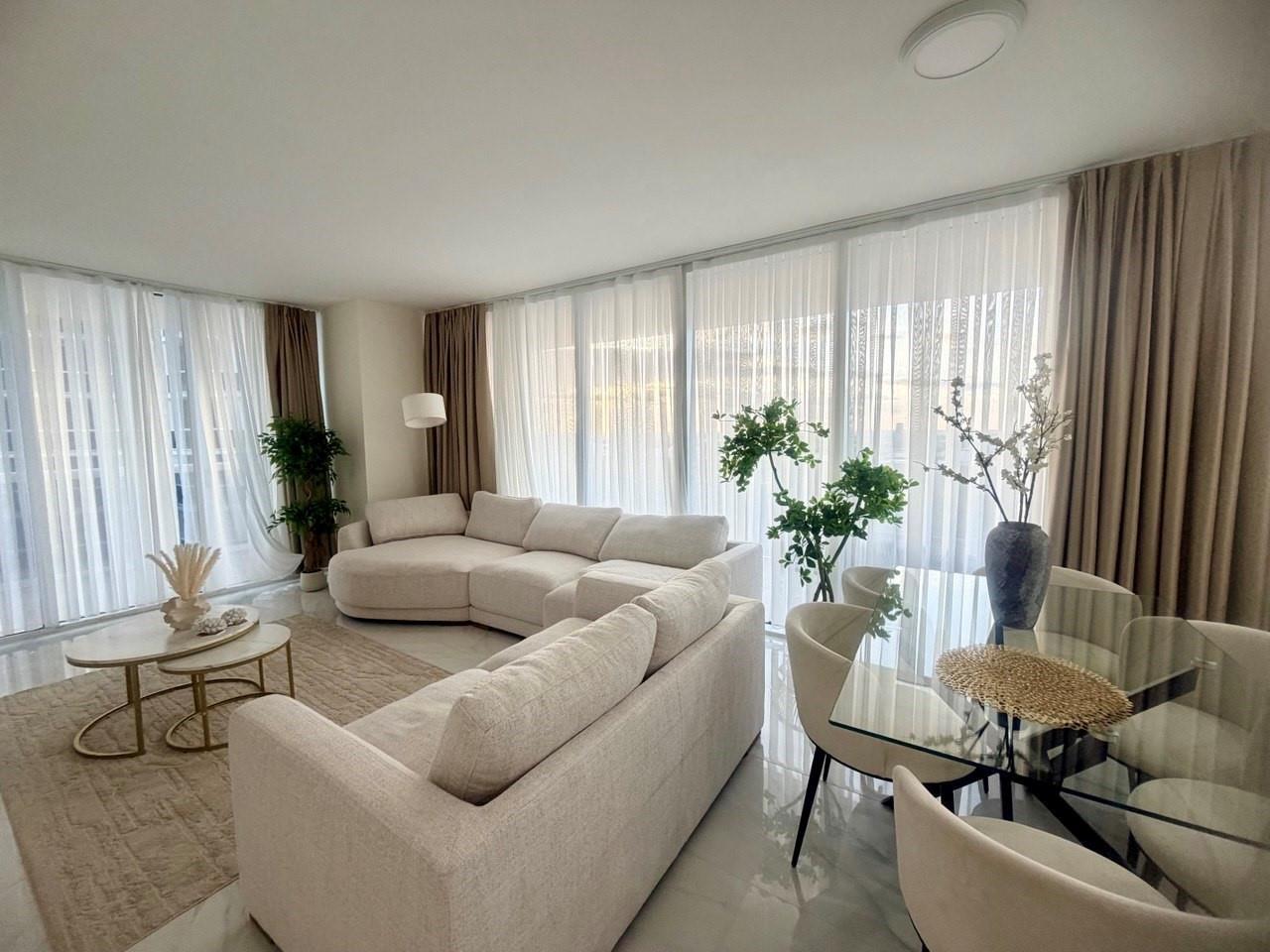 A bright living and dining area features a beige sectional sofa, glass table, and floor-to-ceiling curtains — 1830 S Ocean Drive # 2406, Hallandale Beach FL 33009, HALLANDALE BEACH, FL