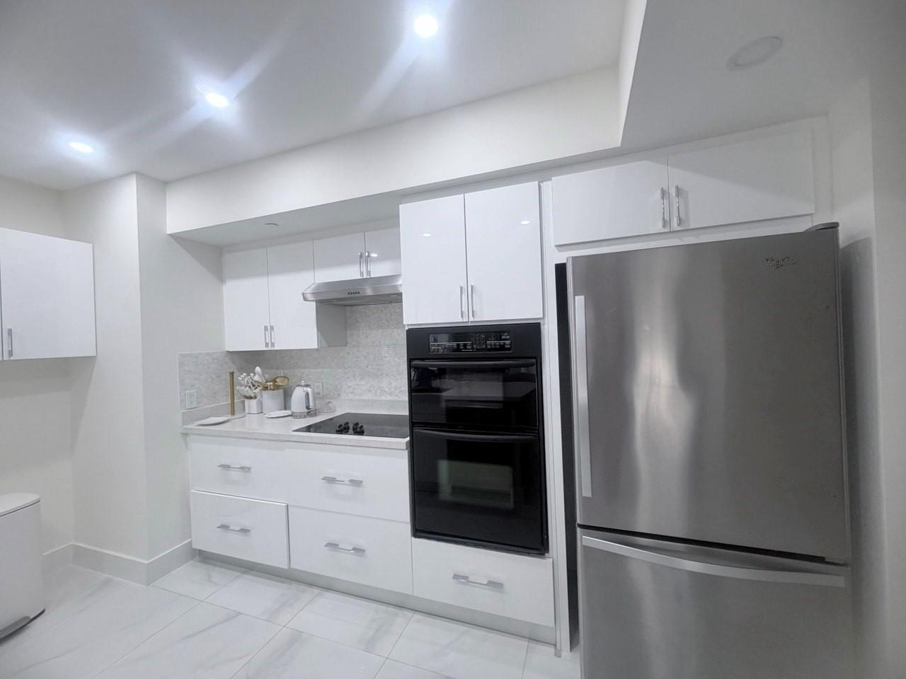 A modern kitchen features white cabinets, stainless steel appliances, and light-colored tiled flooring — 1830 S Ocean Drive # 2406, Hallandale Beach FL 33009, HALLANDALE BEACH, FL
