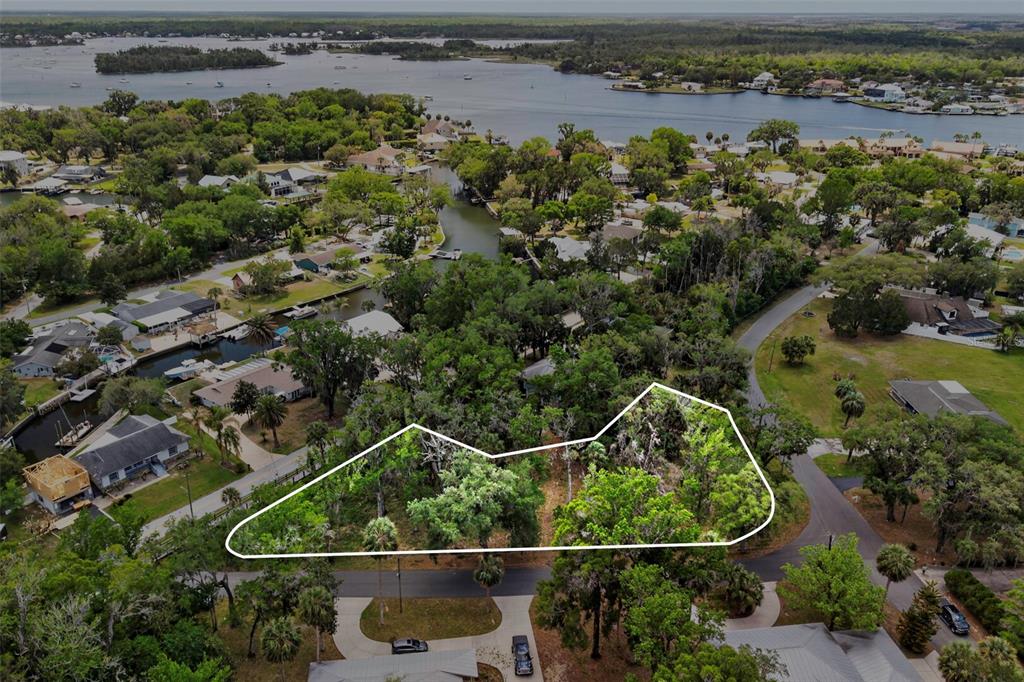 An aerial view shows a wooded, undeveloped residential lot outlined in white near a waterway — 580 NW 14TH PLACE, CRYSTAL RIVER, FL