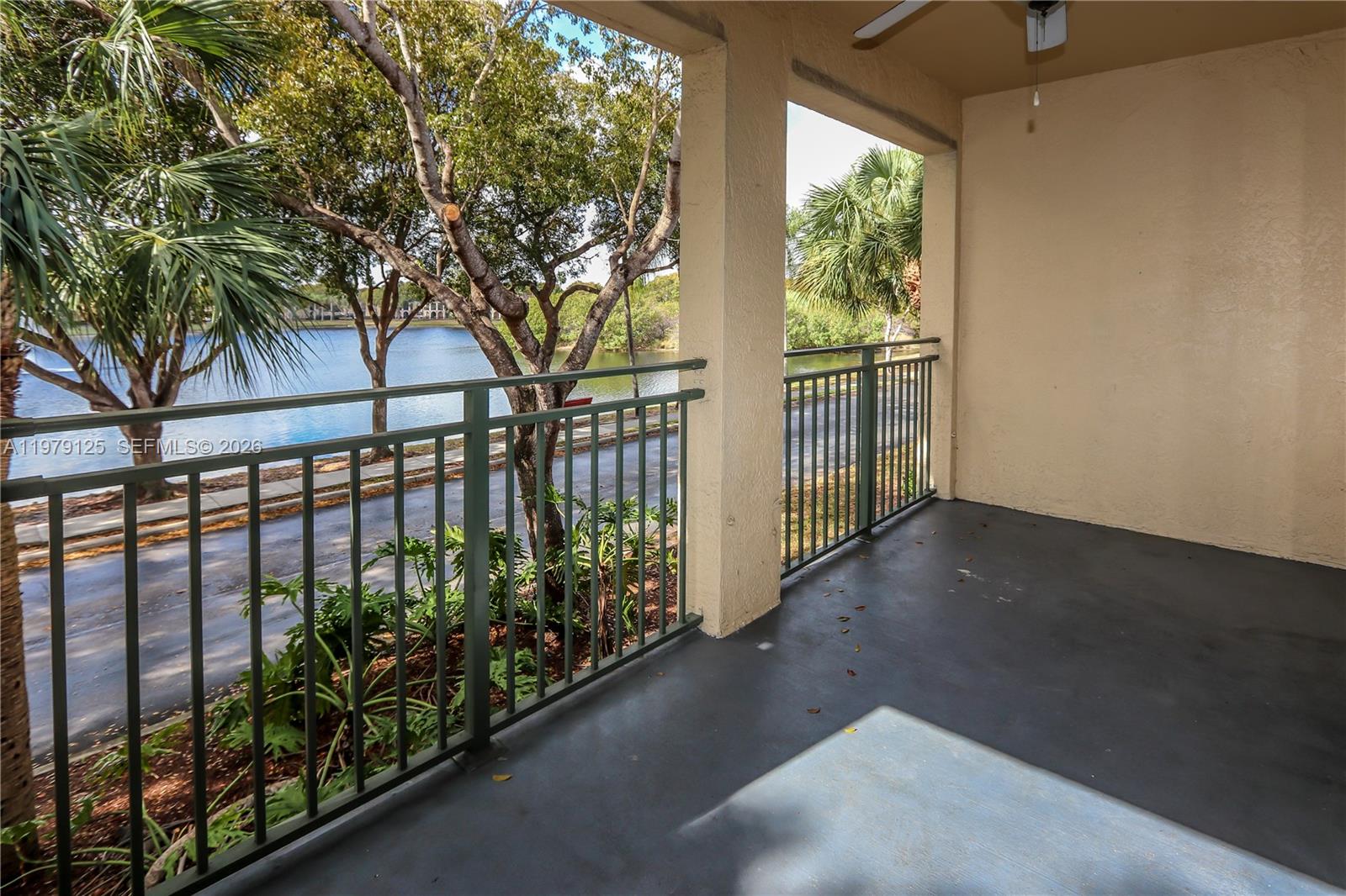 A covered balcony features a dark floor, metal railings, and a view of a lake — 2442 Centergate Dr # 202, Miramar FL 33025, MIRAMAR, FL
