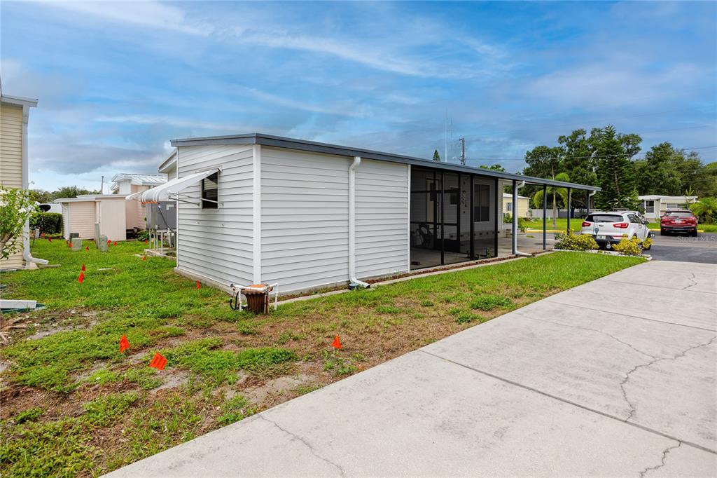 A light-colored mobile home features a screened-in porch and a concrete driveway — 6821 AMERICANA DRIVE NE UNIT 106, ST PETERSBURG, FL