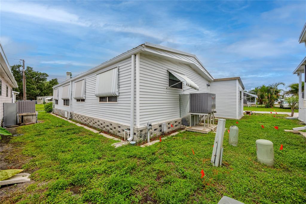 The exterior of a white mobile home features metal awnings and a concrete block foundation — 6821 AMERICANA DRIVE NE UNIT 106, ST PETERSBURG, FL