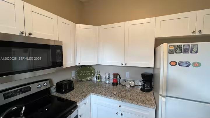 A kitchen features white cabinets, granite countertops, stainless steel appliances, and a white refrigerator — 404 Red Hawk Loop, Winter Haven FL 33880, WINTER HAVEN, FL
