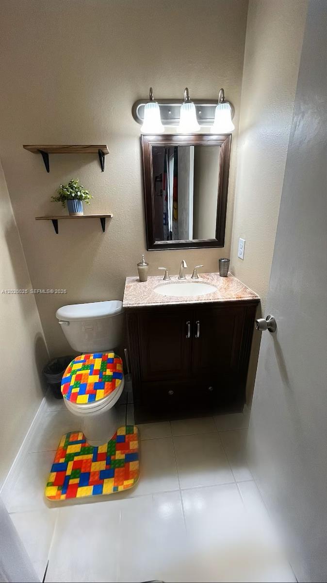 A small bathroom features a dark wood vanity, a mirror, and a colorful block-patterned toilet set — 404 Red Hawk Loop, Winter Haven FL 33880, WINTER HAVEN, FL