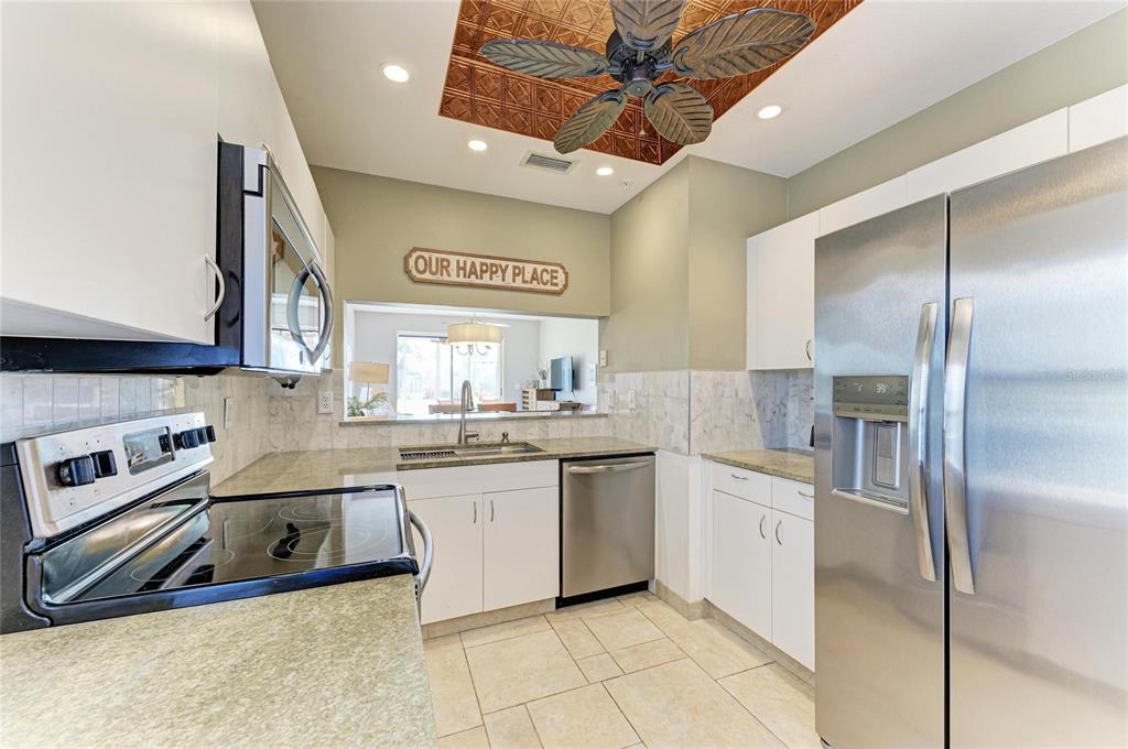 A kitchen features white cabinets, stainless steel appliances, granite countertops, and a decorative ceiling fan — 9620 CLUB SOUTH CIRCLE UNIT 5108, SARASOTA, FL