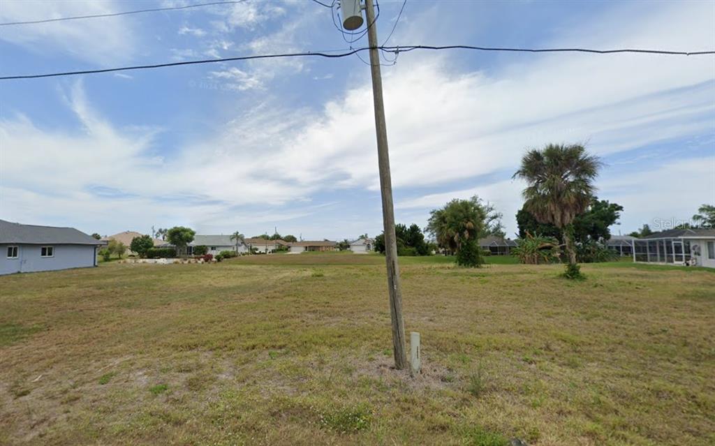 A vacant, grassy residential lot features a utility pole in the foreground under a cloudy sky — 17 FAIRWAY ROAD, ROTONDA WEST, FL