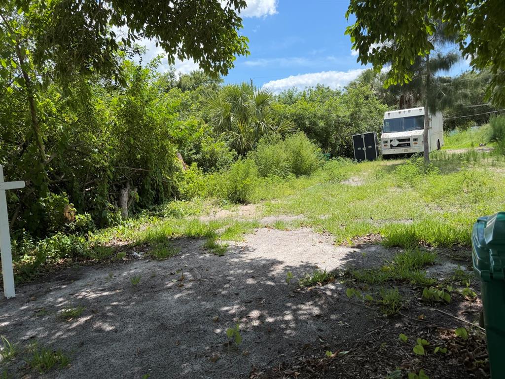 A vacant, grassy lot with a white delivery truck parked near dense trees and foliage — 5497 MAZE DRIVE, PUNTA GORDA, FL
