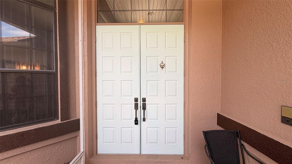 A white double front door with a transom window is set within a tan entryway — 2496 E NEWHAVEN STREET, INVERNESS, FL