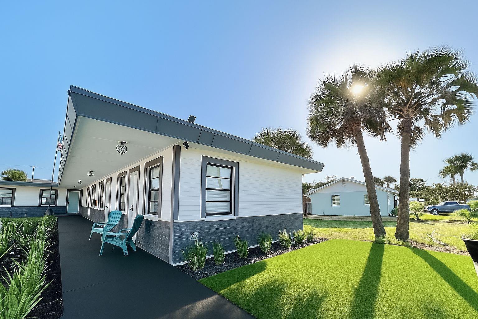 A white building with gray stone accents features a covered porch and artificial turf lawn — 1915 N Atlantic Avenue, FL 32118, FL