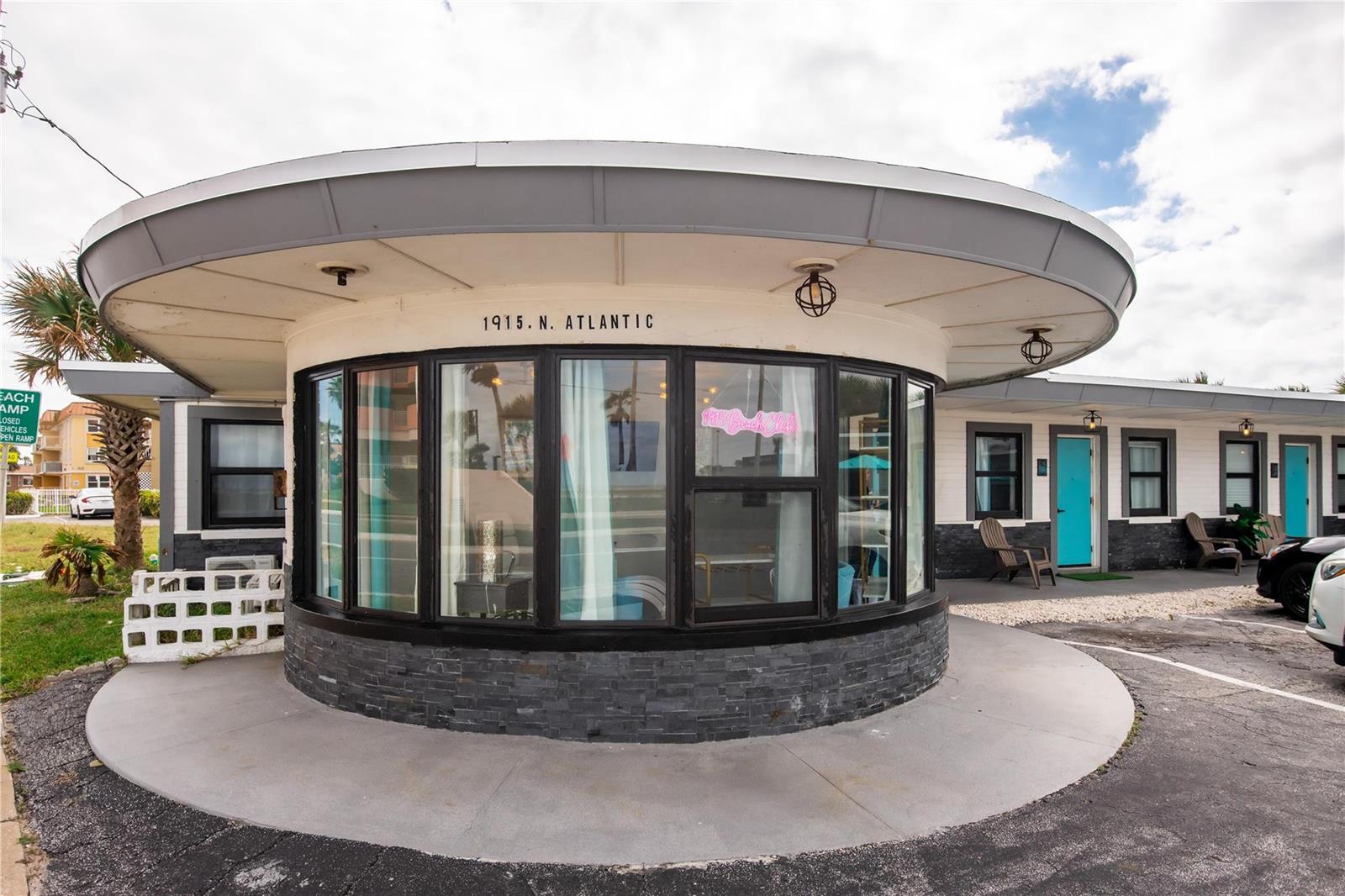 A circular, mid-century modern building exterior features a stone base, large windows, and a roof overhang — 1915 N Atlantic Avenue, FL 32118, FL